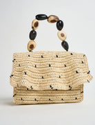 Woven handbag with a beaded handle on a light gray background