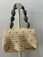 Woven handbag with blue accents on a gray background