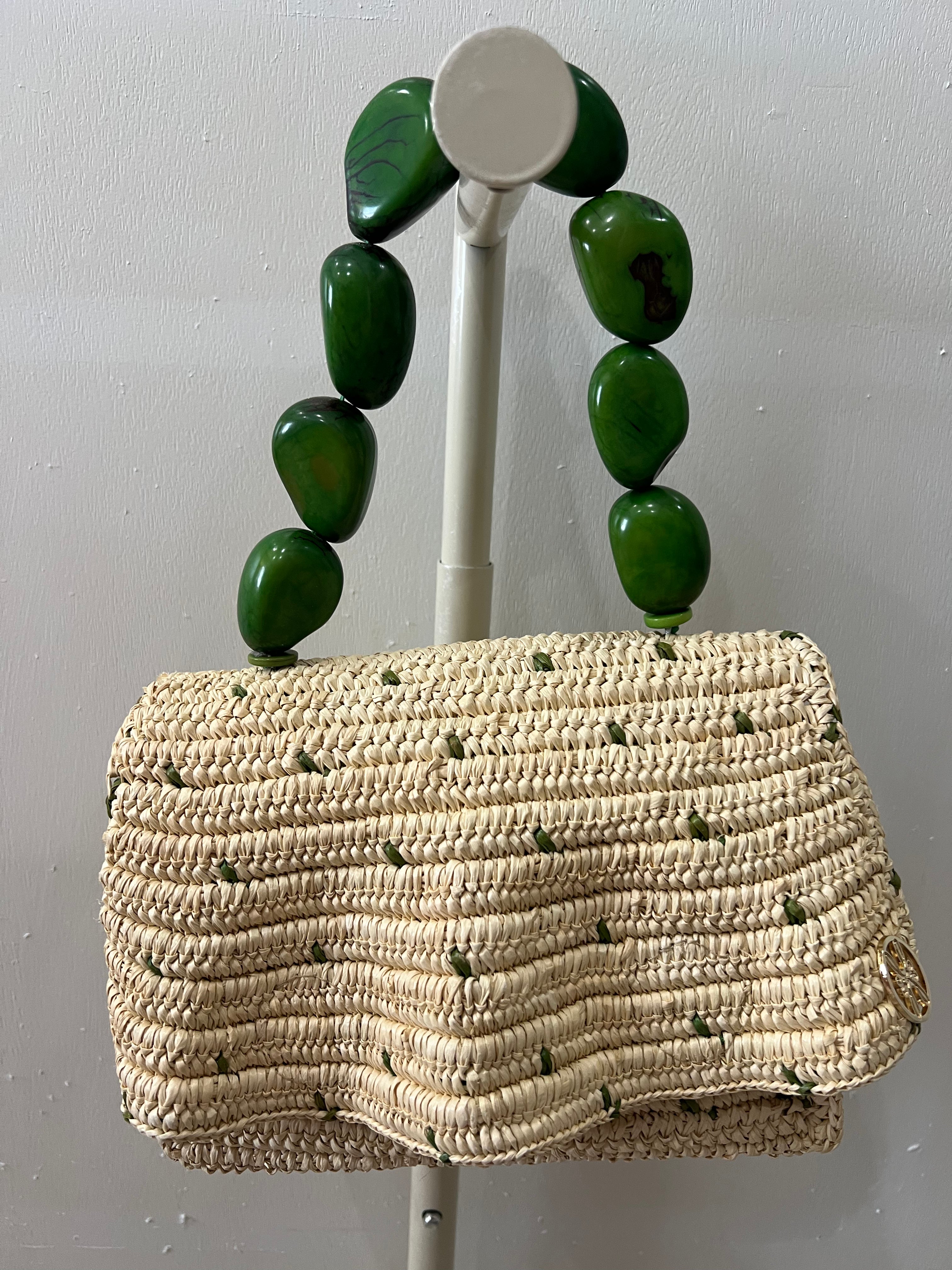 Woven handbag with green bead handles on a gray background