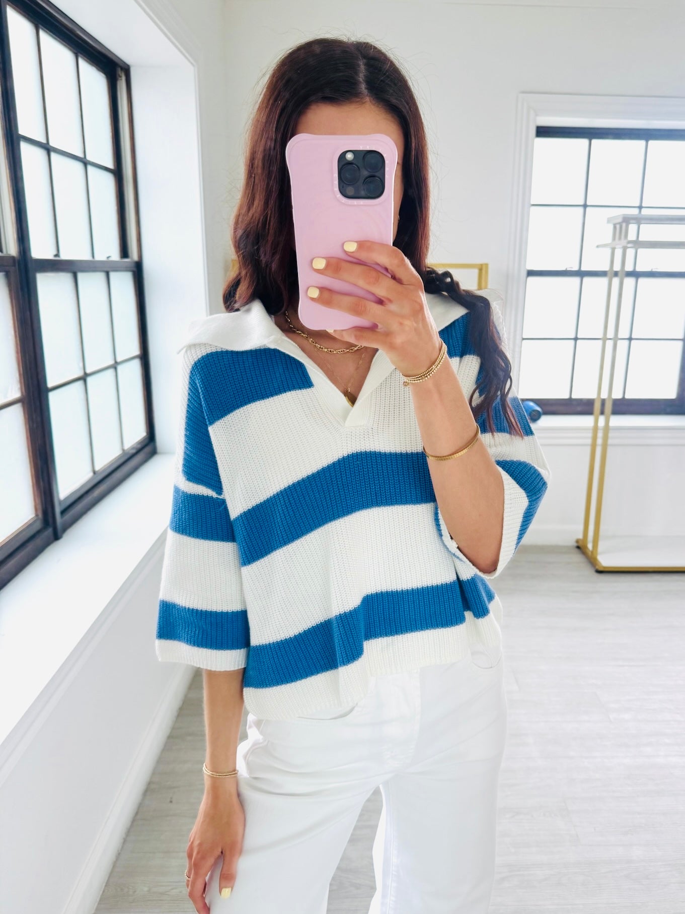 Person wearing a blue and white striped sweater in a bright room.