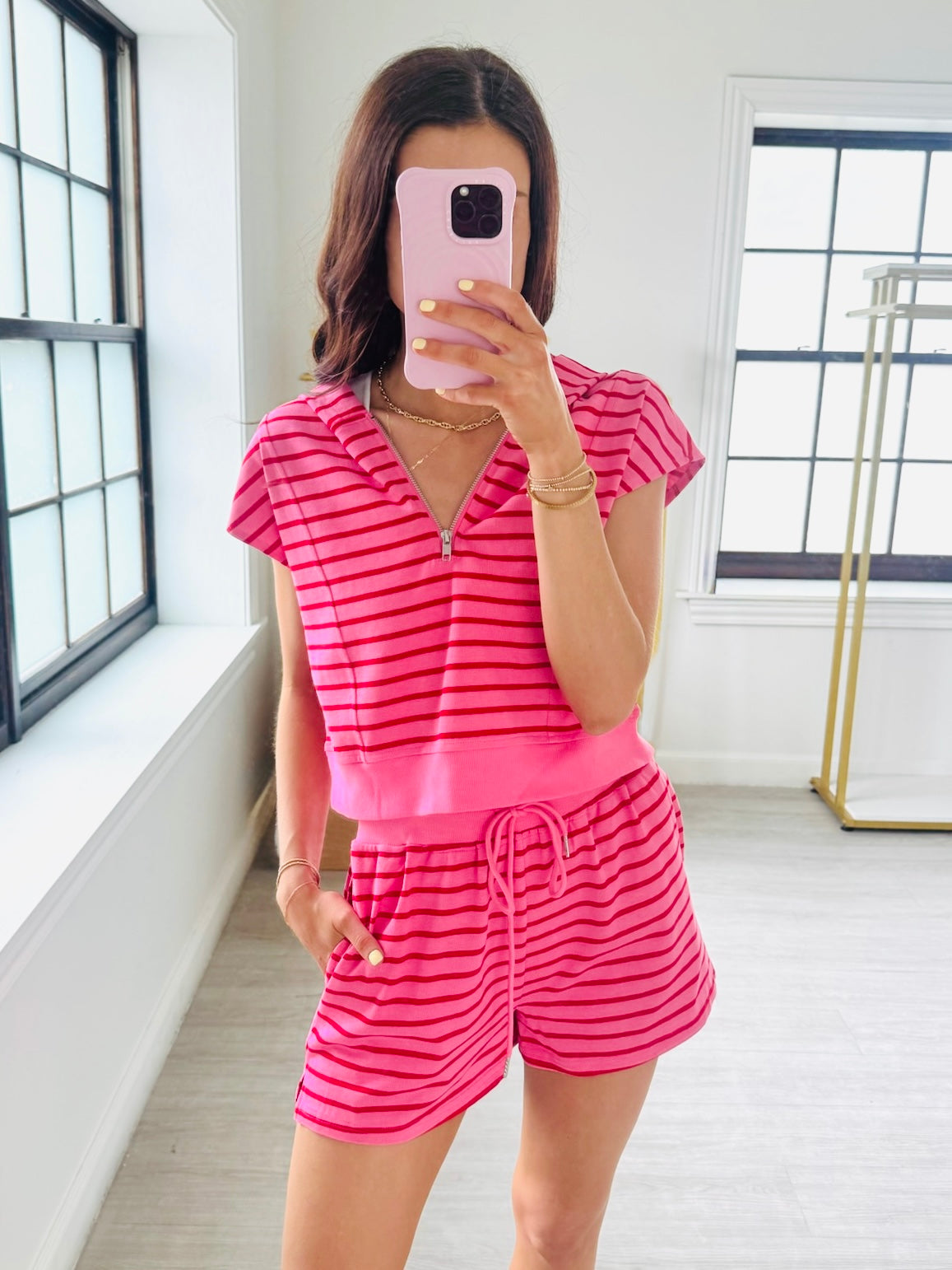 Person wearing a pink and red striped romper taking a mirror selfie.