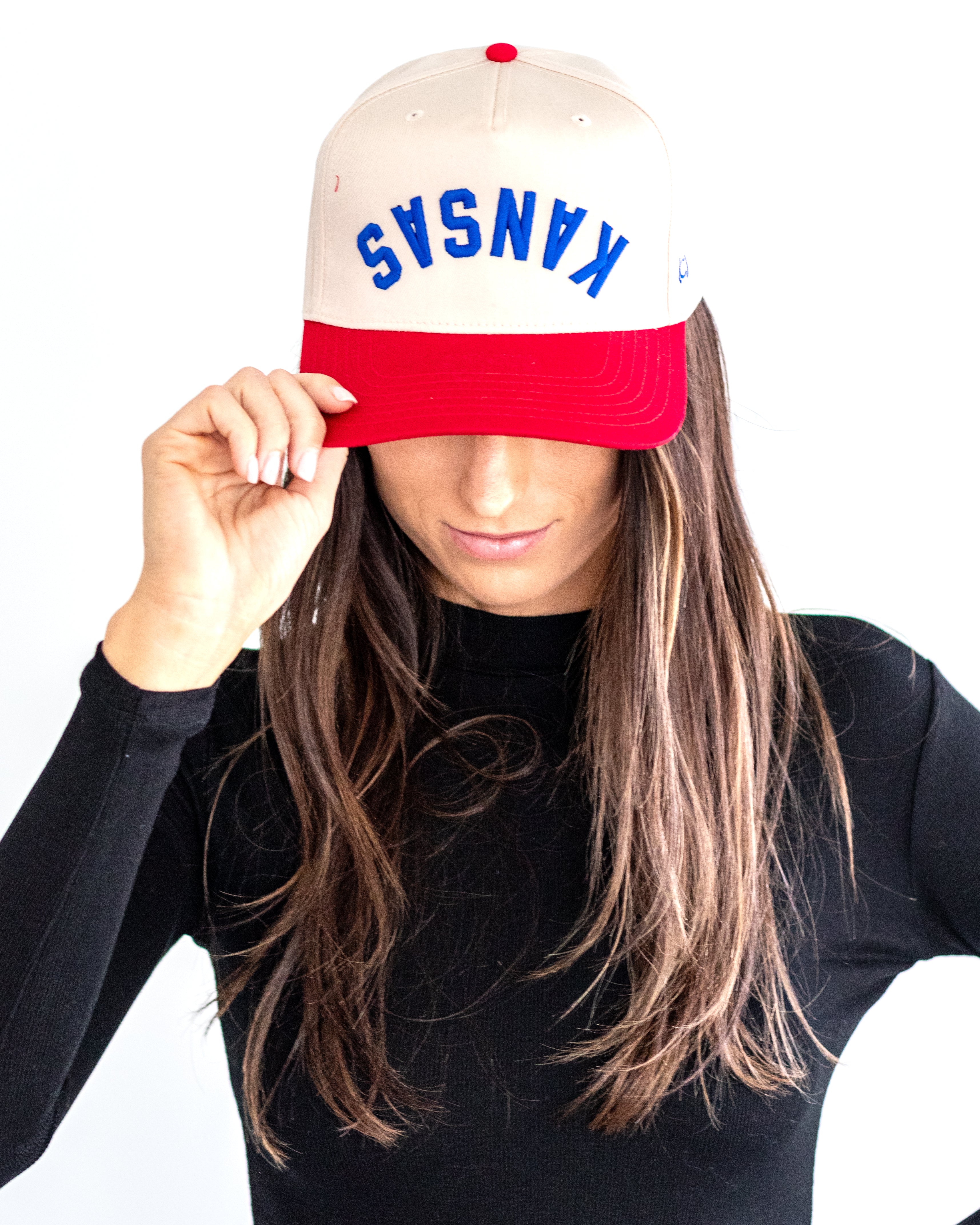 Person wearing a red and white cap with embroidered 'Kansas' in blue text on a white background
