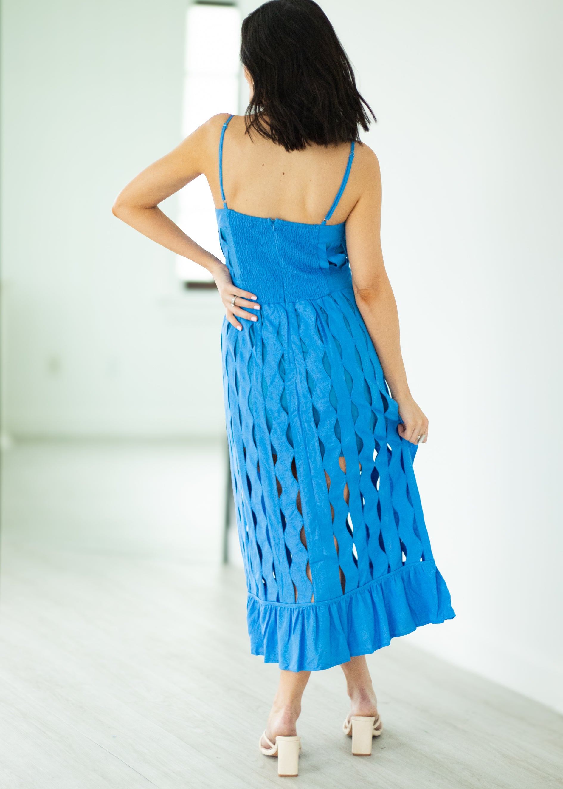 Woman wearing a blue dress with cut-out design on a white background