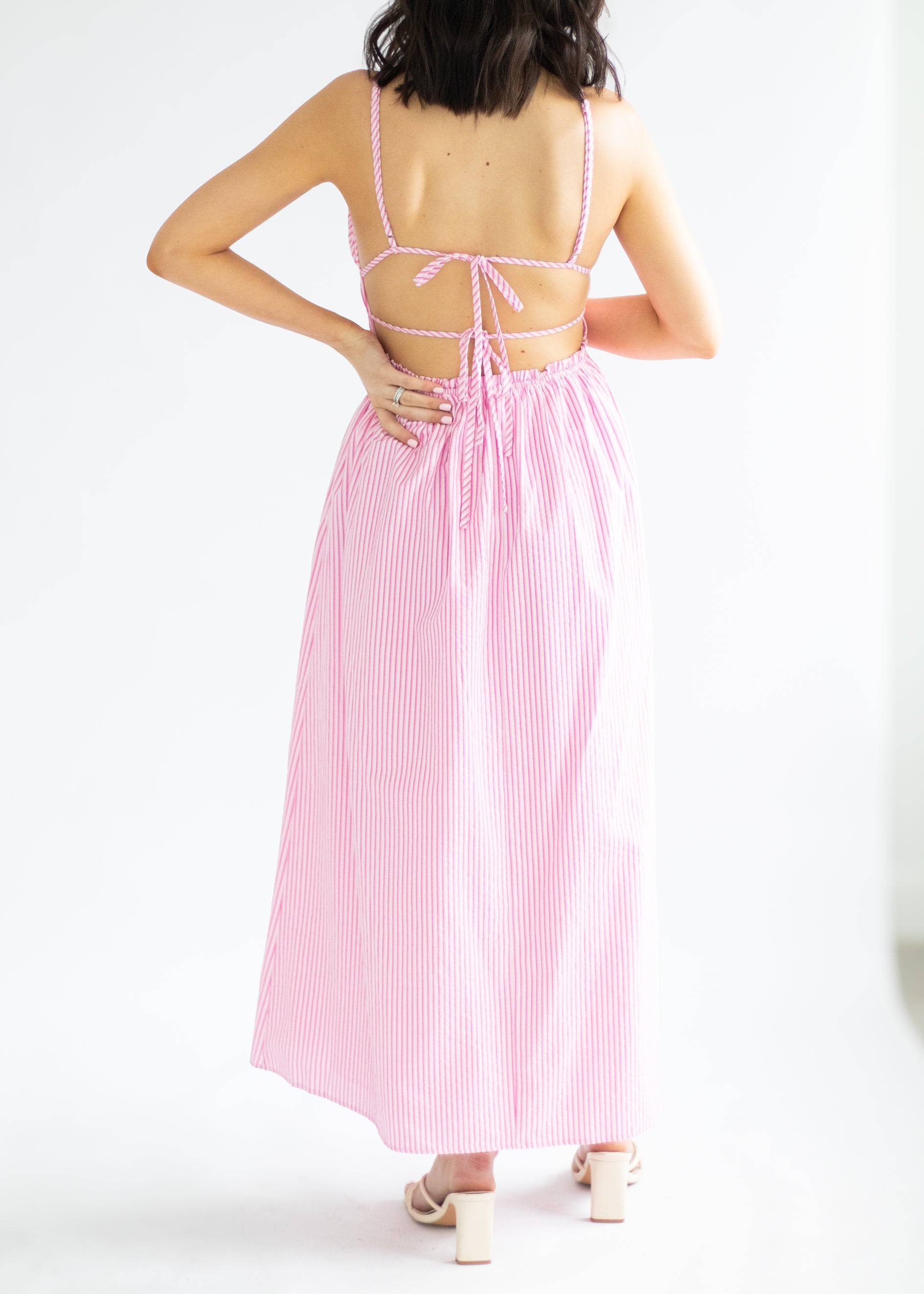 Woman wearing a pink and white striped dress on a white background