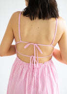 Pink and white striped dress with open back on a plain background