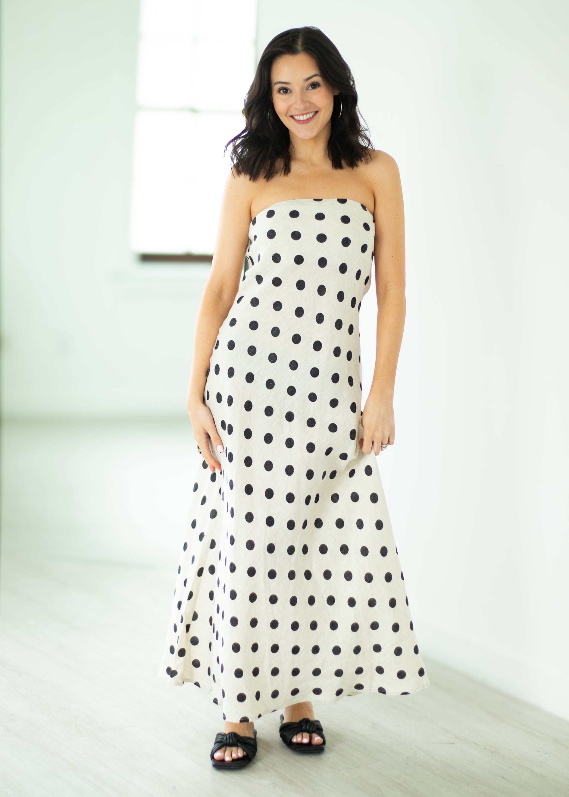 Woman wearing a strapless polka dot dress against a white background