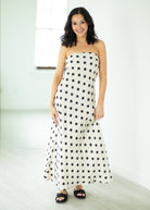 Woman wearing a strapless polka dot dress against a white background