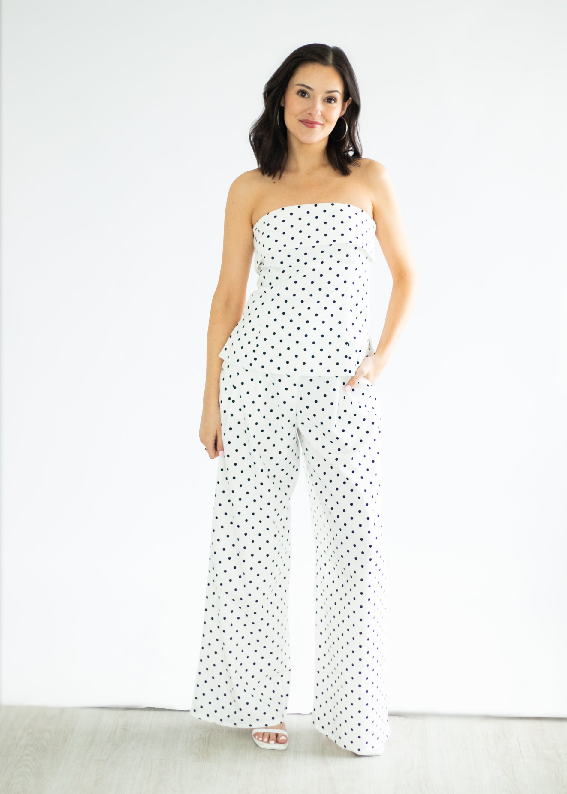 Woman wearing a strapless polka dot jumpsuit on a white background