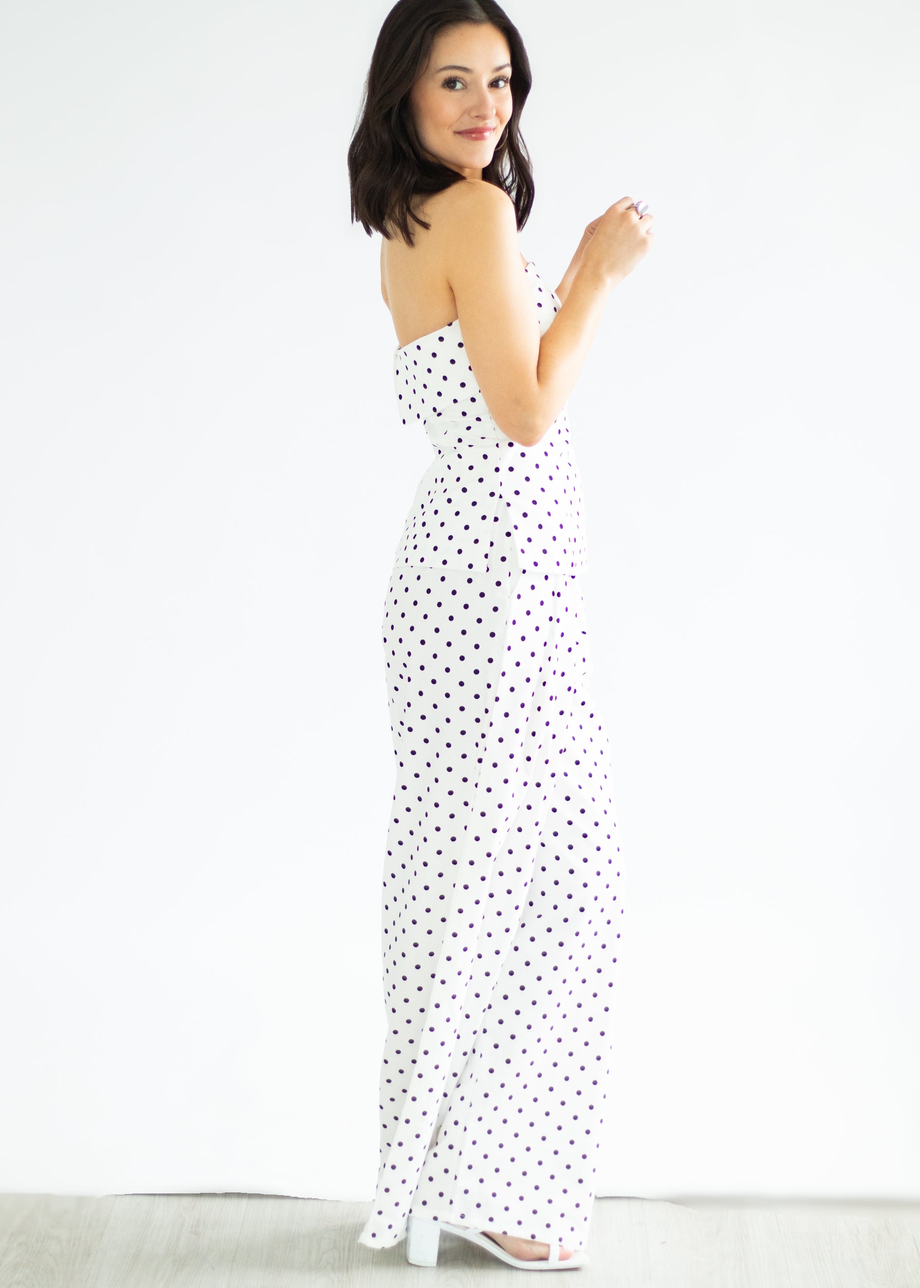 Woman wearing a strapless polka dot dress on a white background