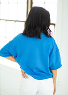Person wearing a blue sweater in a bright room