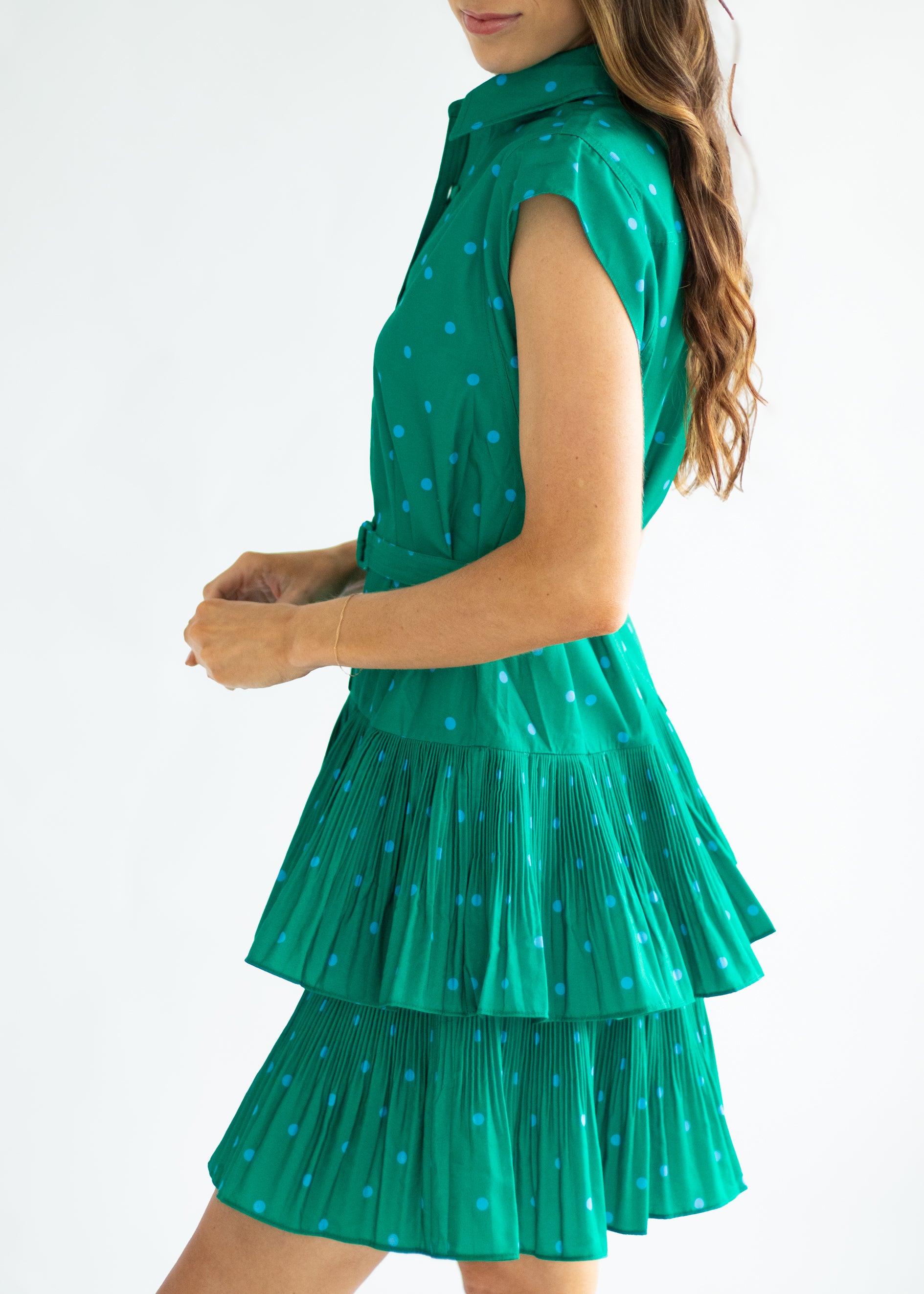 Green tiered dress with white polka dots worn by a person on a white background