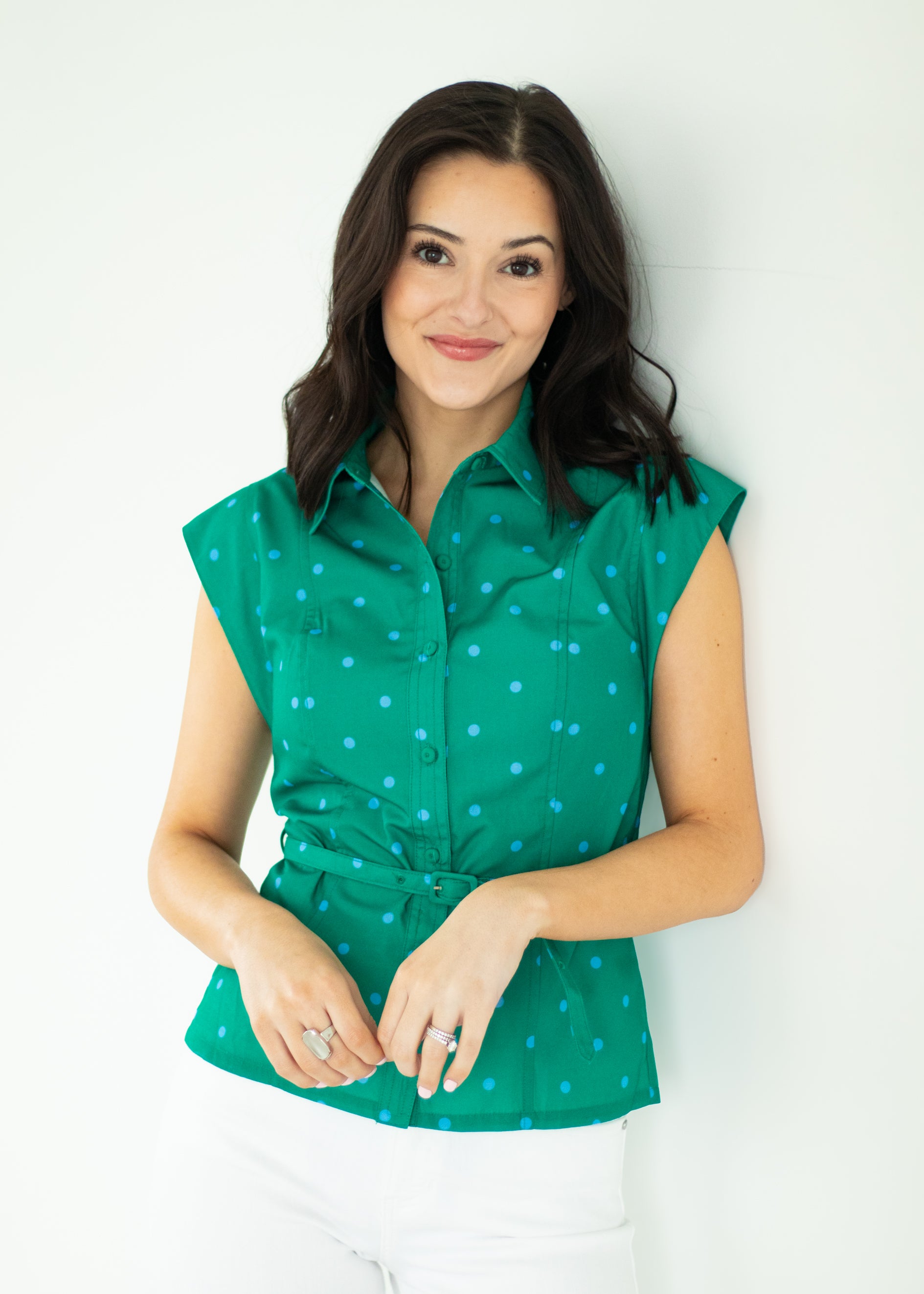 Woman wearing a green polka dot blouse against a white background