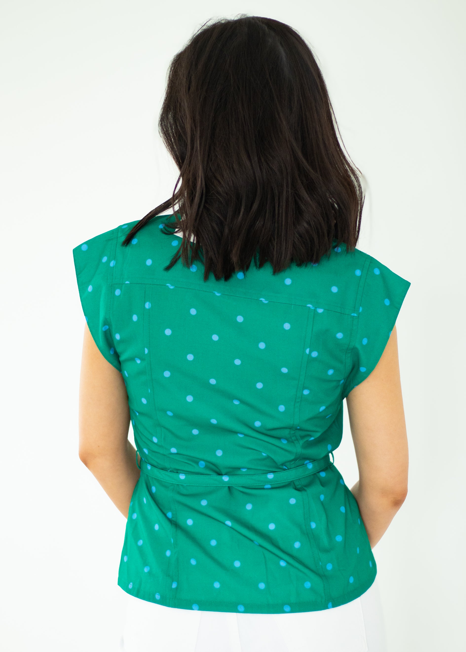 Woman wearing a green polka dot top against a white background