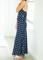 Woman wearing a navy blue polka dot dress in a bright room.