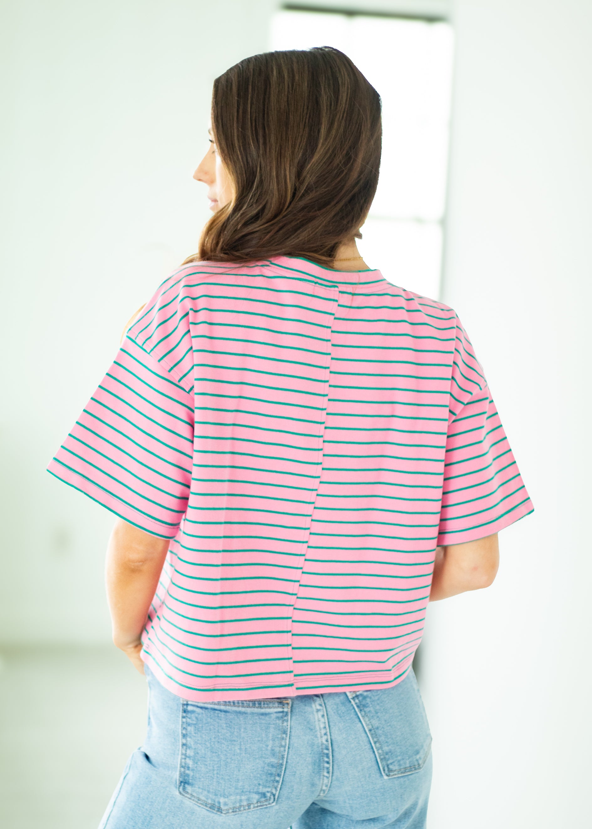 Person wearing a pink and white striped shirt with a blurred background