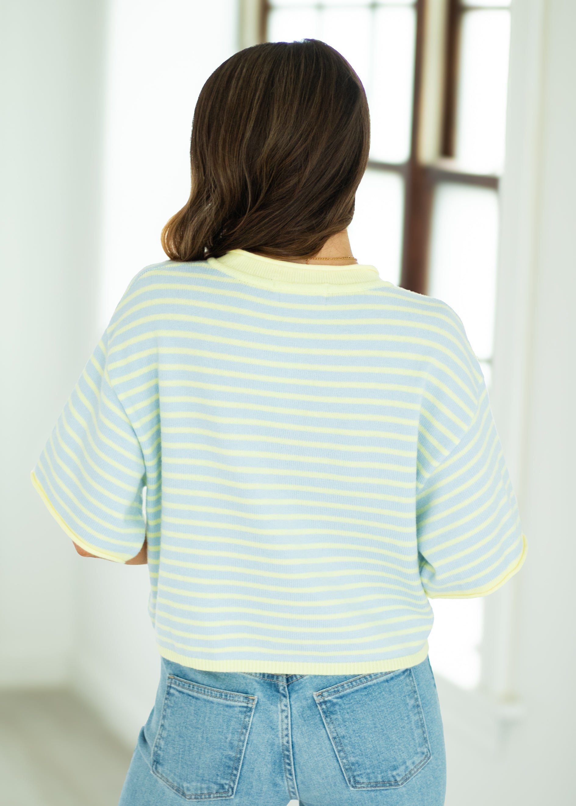 Person wearing a beige long-sleeve top and floral skirt on a white background