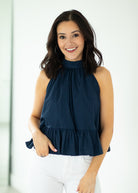 Woman wearing a navy blue sleeveless top with a white background