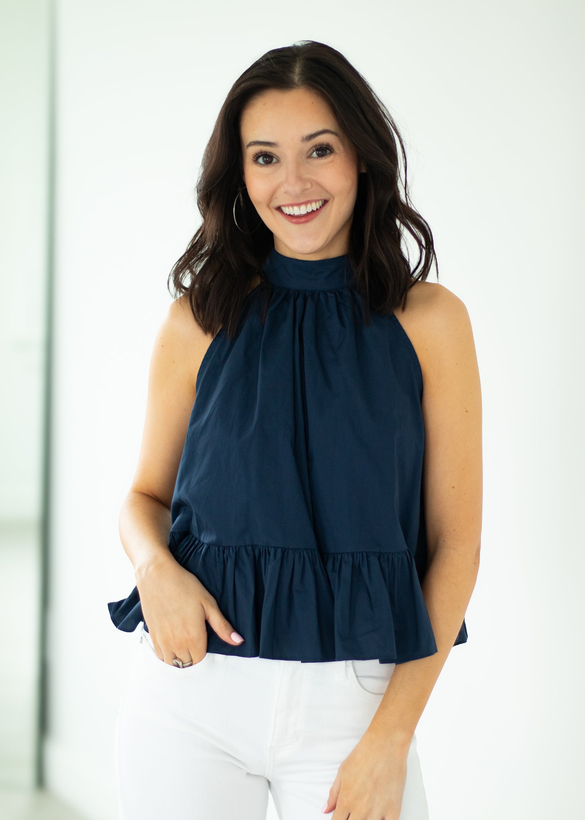 Woman wearing a navy blue sleeveless top with a white background