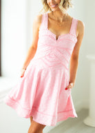 Woman wearing a pink lace dress against a white background