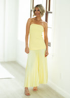 Woman wearing a yellow strapless dress in a bright room