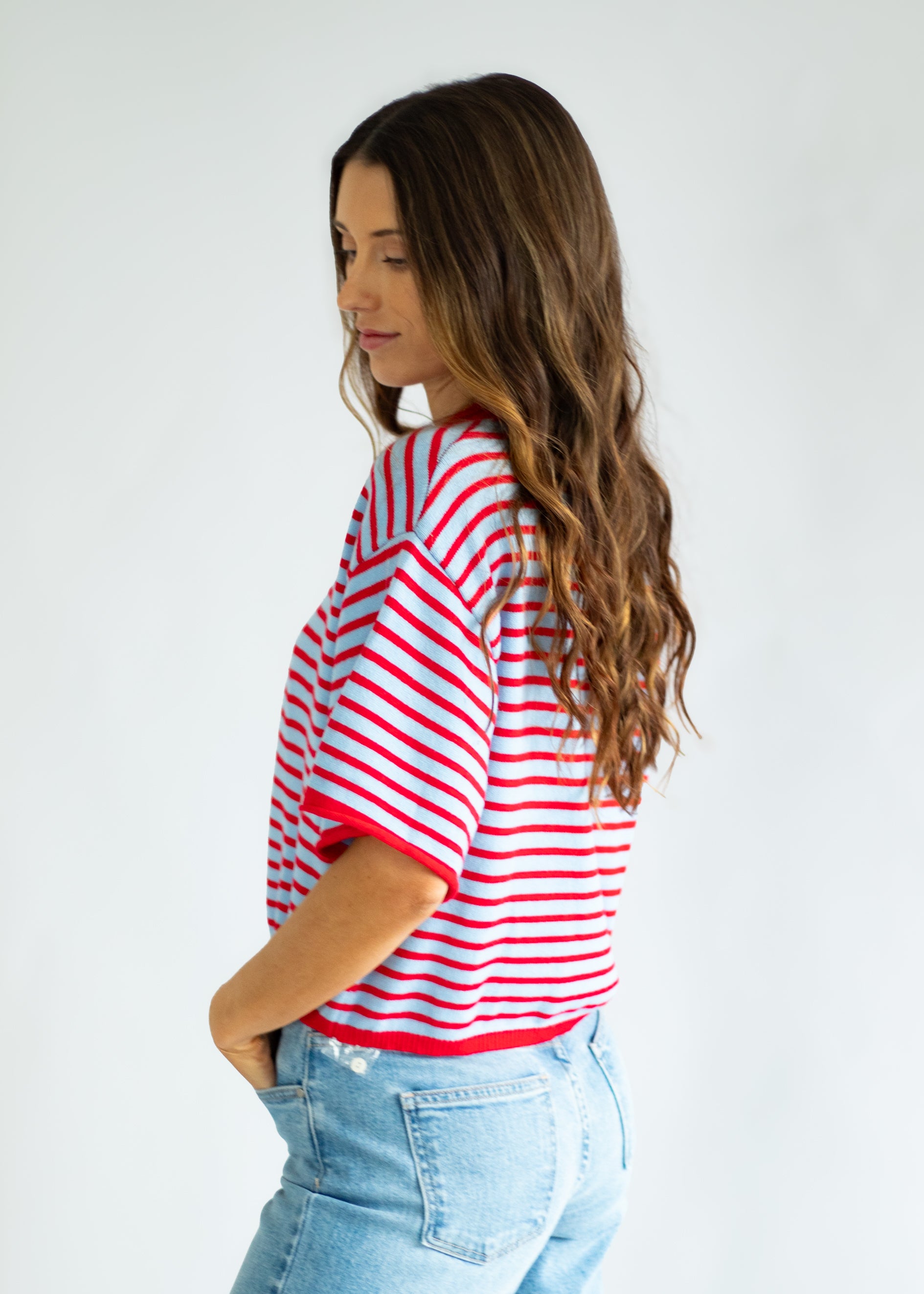 Woman wearing a red and white striped shirt and blue jeans against a white background