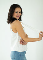 Woman wearing a white sleeveless top and blue jeans on a white background
