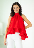 Woman wearing a red halter top with ruffled layers against a white background