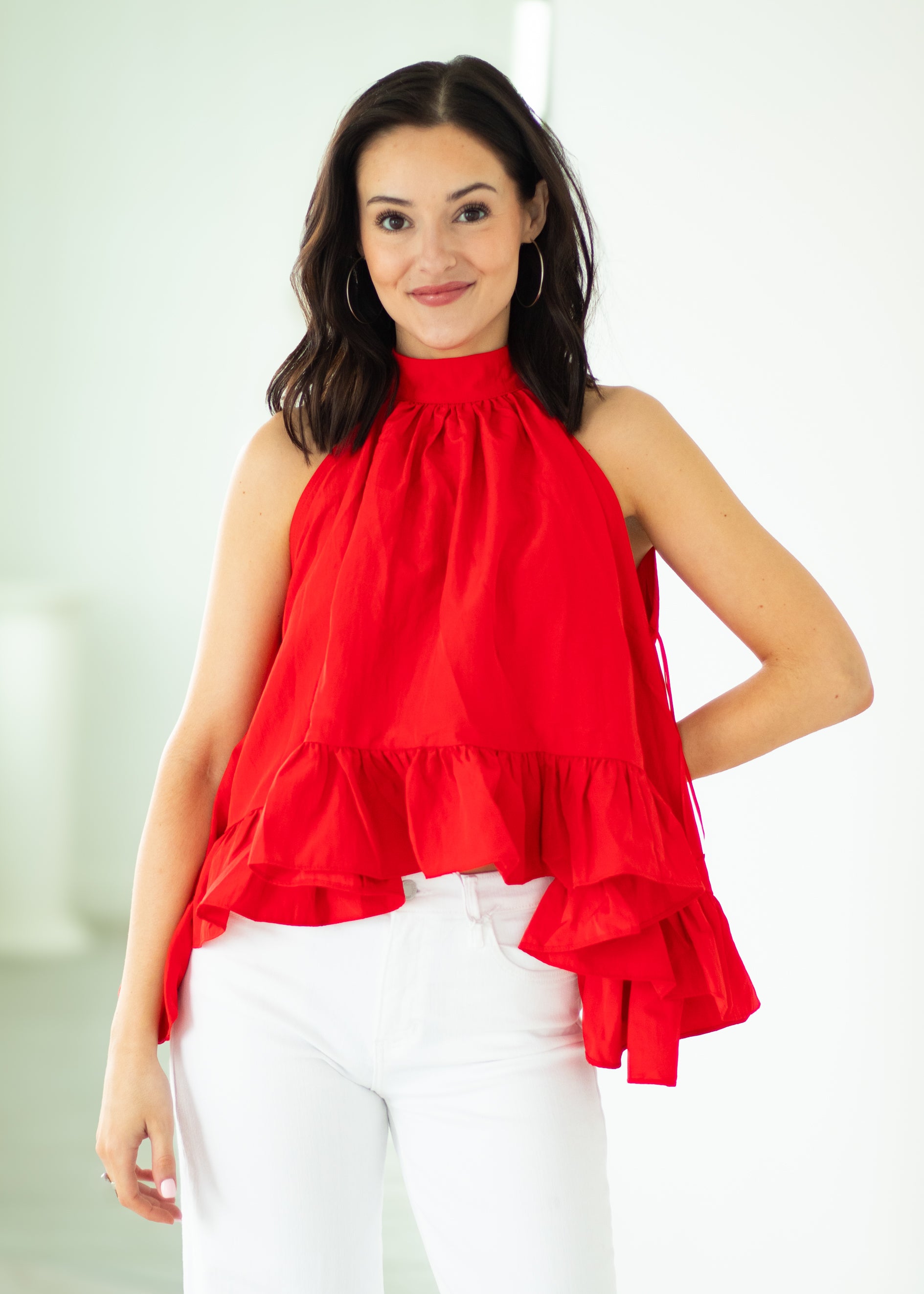 Woman wearing a red halter top with ruffled layers against a white background