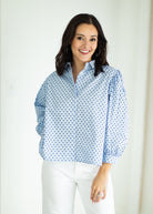 Woman wearing a light blue polka dot shirt against a white background