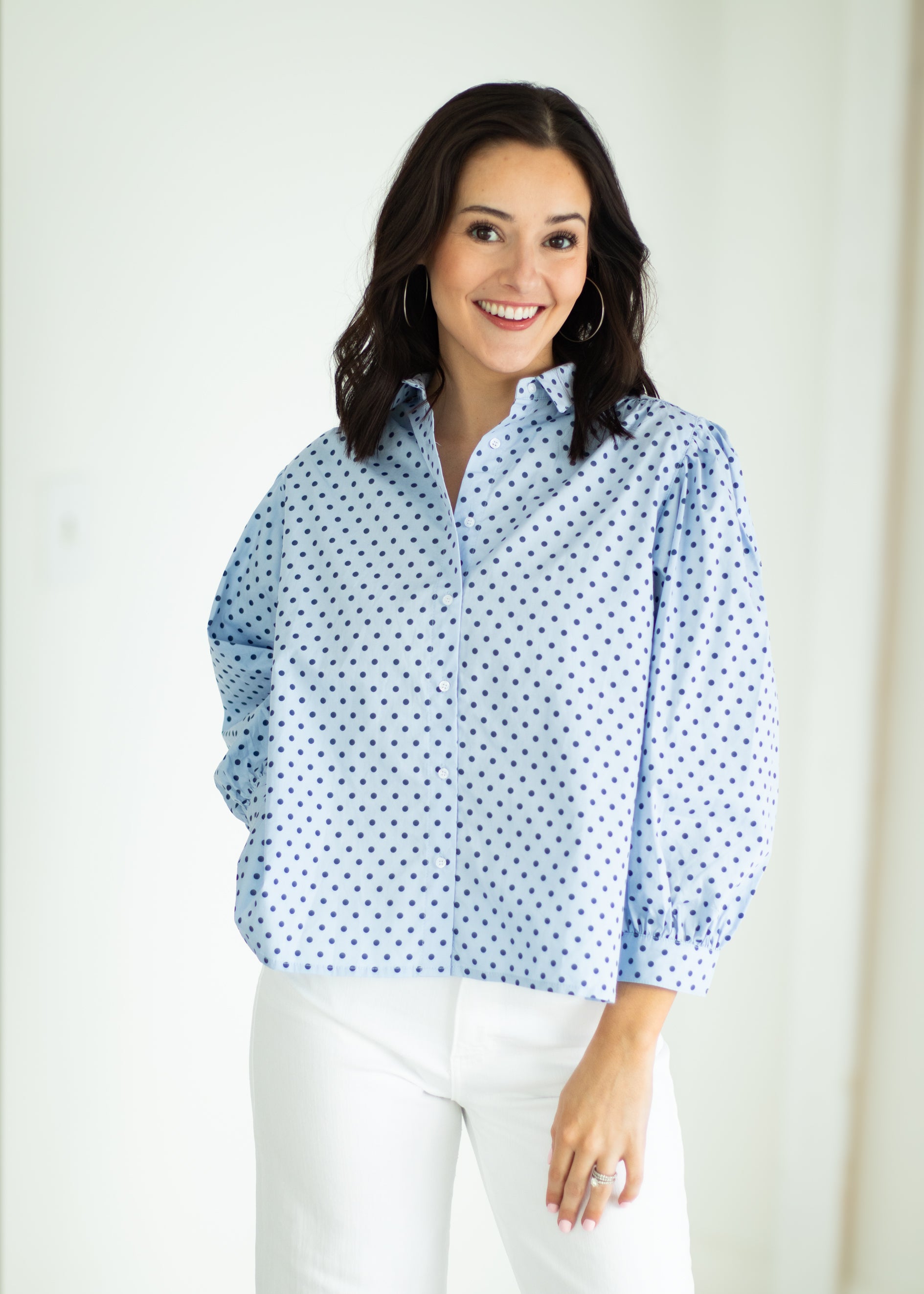 Woman wearing a light blue polka dot shirt against a white background