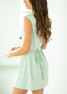 Woman wearing a light green dress with a plain background