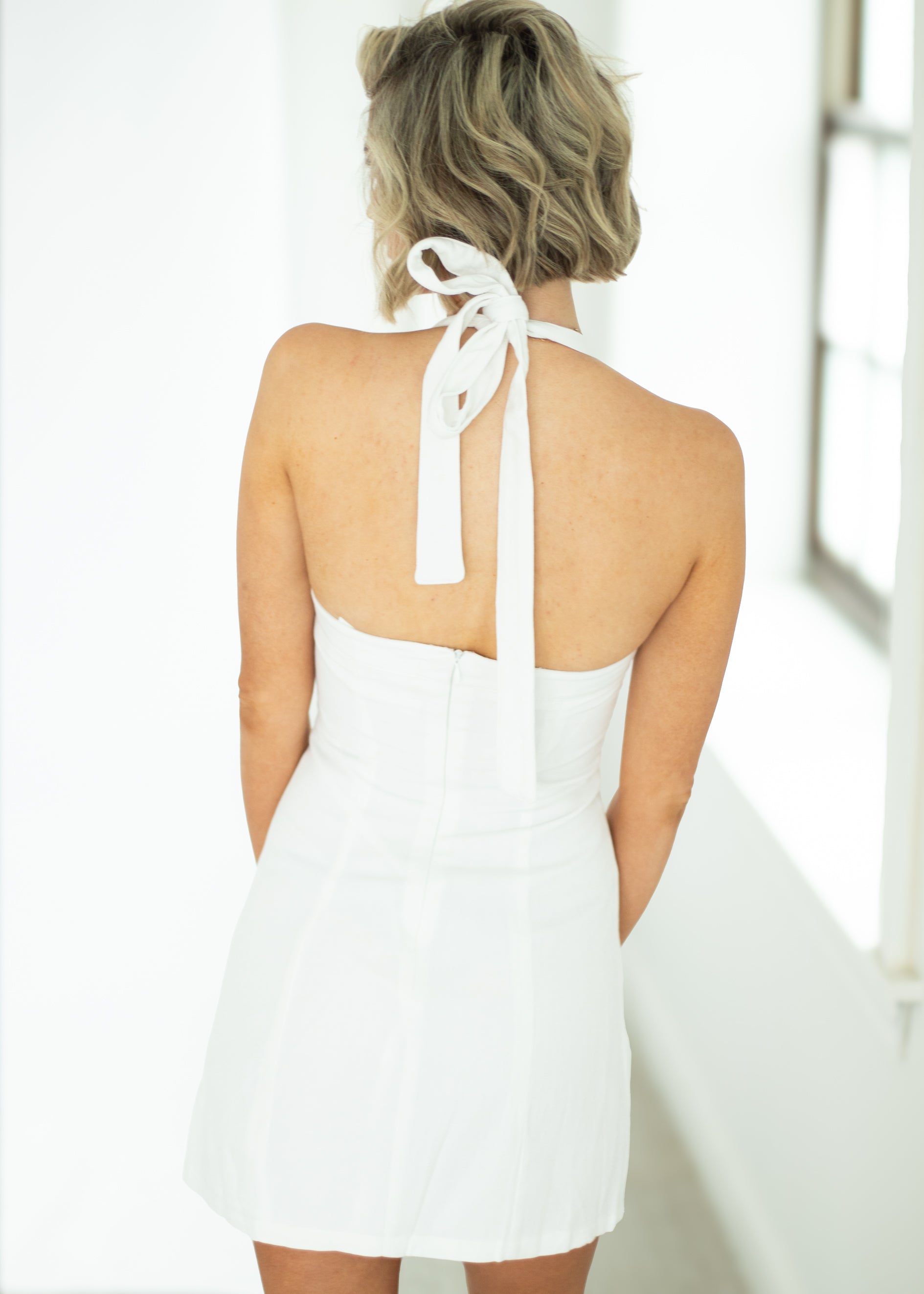 Woman wearing a white halter neck dress with a blurred background