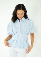 Woman wearing a light blue striped shirt against a white background