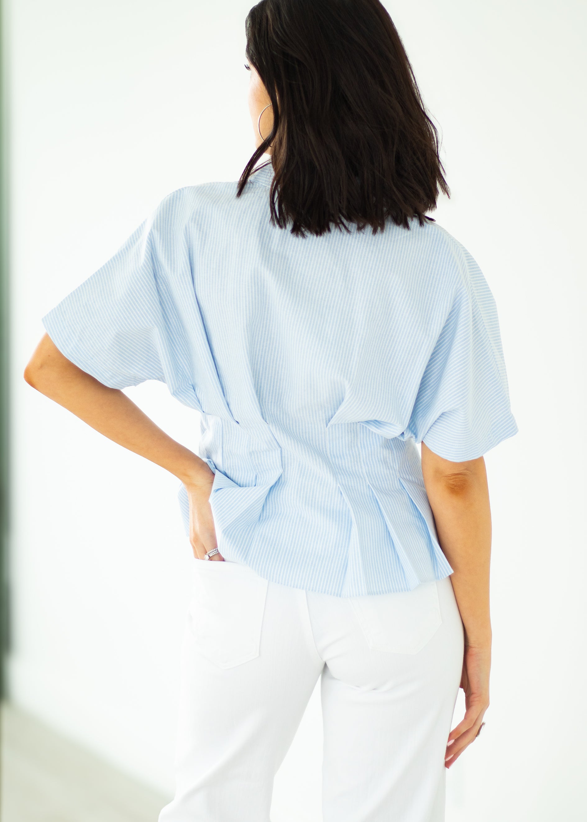 Woman wearing a light blue blouse with a tie-waist design on a white background