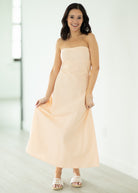 Woman wearing a strapless beige dress against a white background