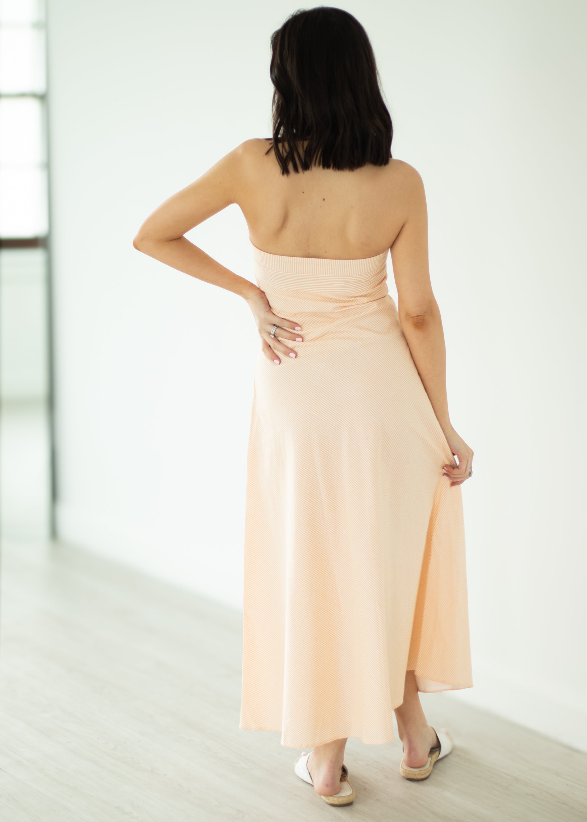 Woman wearing a peach strapless dress in a minimal indoor setting