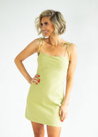 Woman wearing a light green checkered dress against a white background