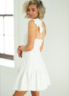 Woman wearing a white dress with floral details in a bright room