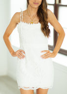 Woman wearing a white lace dress with a plain background