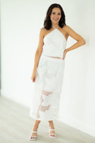 Woman wearing a white dress with sheer panels on a plain background