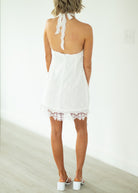 Woman wearing a white lace dress with a plain background