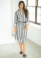 Woman wearing a black and white patterned dress in a bright room.