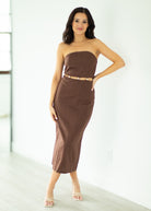 Woman wearing a brown strapless dress against a white background