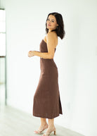 Woman wearing a brown dress standing against a white background