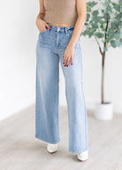 Person wearing light blue jeans with a neutral background