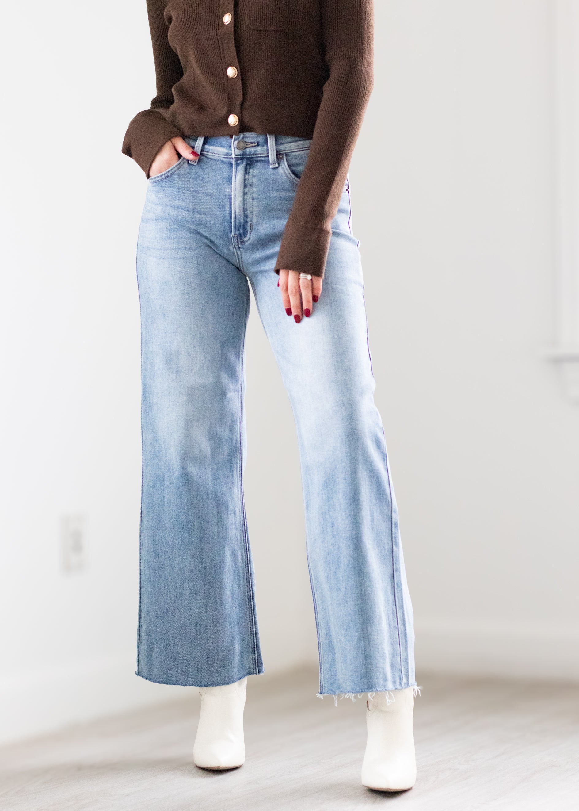 Person wearing light blue jeans and a brown cardigan on a plain background