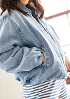 Person wearing a light blue denim jacket over a striped shirt.