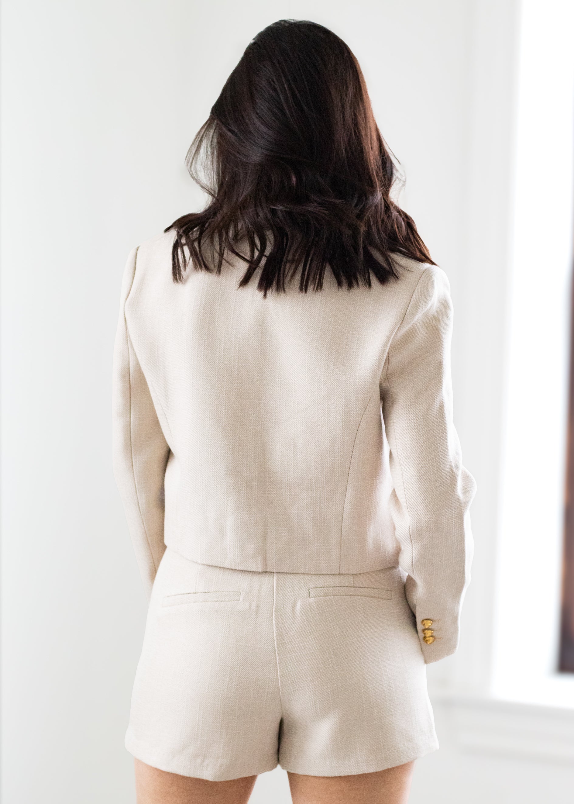 Person wearing a beige suit with shorts on a white background