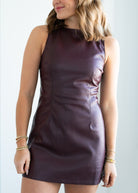 Woman wearing a sleeveless, dark purple dress against a plain background