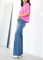 Woman wearing a pink top and blue jeans against a white background